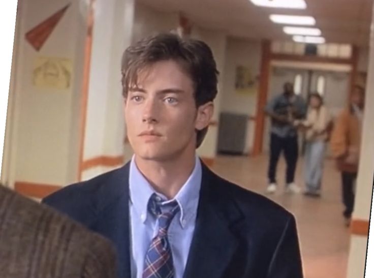 a man wearing a suit and tie standing in a hallway