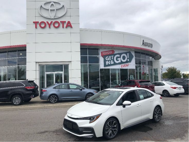 the front of a toyota dealership with several cars parked in front and one is white