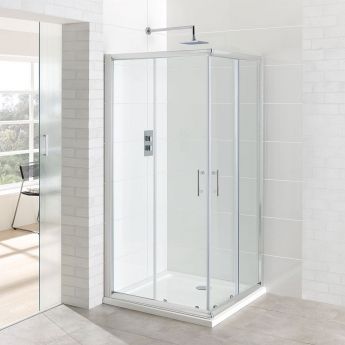 a bathroom with a walk in shower next to a white brick wall and tiled floor