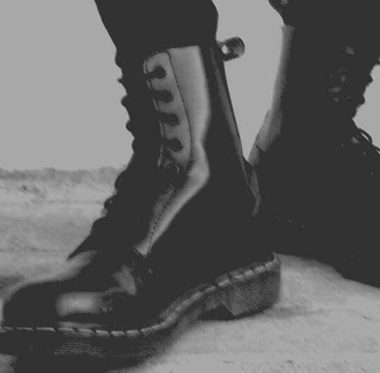 black and white photograph of someone's legs wearing boots