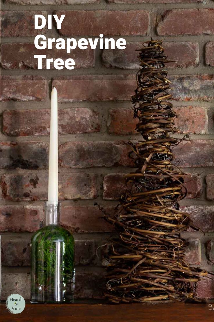 A cone shaped tree made from grapevines sits on a mantle with a bottle and candle. Things To Make With Grape Vines, Hanging Grapevine Wreath From Ceiling, Grapevine Trees Diy How To Make, Grapevine Craft Ideas, Grapevine Garland Christmas Tree, Crafts With Grape Vines, Grapevine Garland Front Door Christmas, Grapevine Christmas Trees, Grapevine Swag Ideas