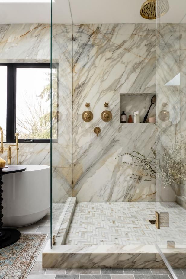 a bathroom with marble walls and flooring next to a bathtub in the corner