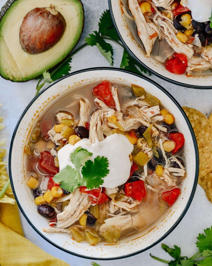 two bowls of chicken tortilla soup with avocado and sour cream