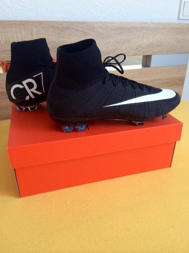 a pair of black and white soccer shoes on top of a red box with the word cr7 printed on it