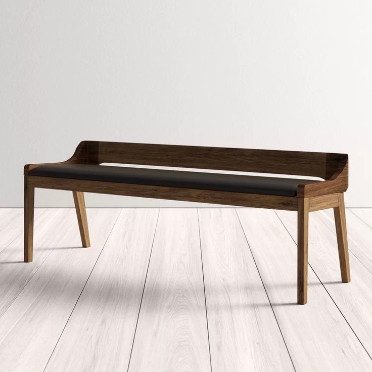 a wooden bench sitting on top of a hard wood floor next to a white wall