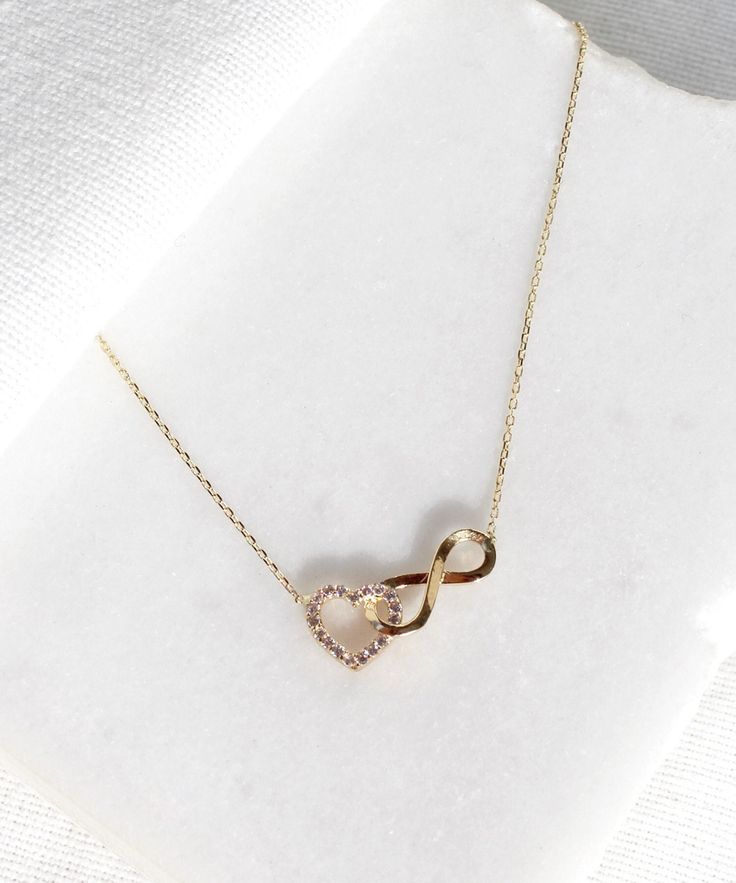 14K Gold Heart and Infinity Symbol Necklace A symbol of infinite love, this elegant necklace showcases the symbols of love and eternity entwined with each other. The heart motif perfectly complements the infinity symbol for a truly romantic look. This unique necklace is perfect for everyday wear as it is made of solid gold and won't tarnish. It is a wonderful gift for a special person. Features: * This necklace is made of patented 14K solid gold. * Length: 42 cm Packaging: You will get your jewe Elegant Rose Gold Infinity Necklace, Diamond Infinity Necklace For Gift, Cubic Zirconia Infinity Necklace For Anniversary, Infinity Necklace With Diamond Accents For Gifts, Infinity Jewelry With Diamond Accents For Gift, Dainty Infinity Necklace For Anniversary, Infinity Cubic Zirconia Necklace For Mother's Day, Sterling Silver Infinity Necklace Fine Jewelry, Mother's Day Infinity Necklace With Cubic Zirconia