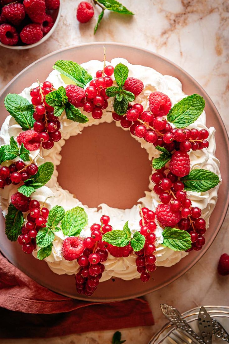 a cake decorated with berries and mints on top of a wooden board next to other decorations