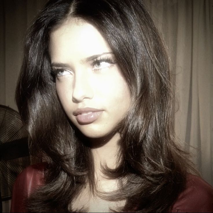 a woman with long brown hair is looking at the camera