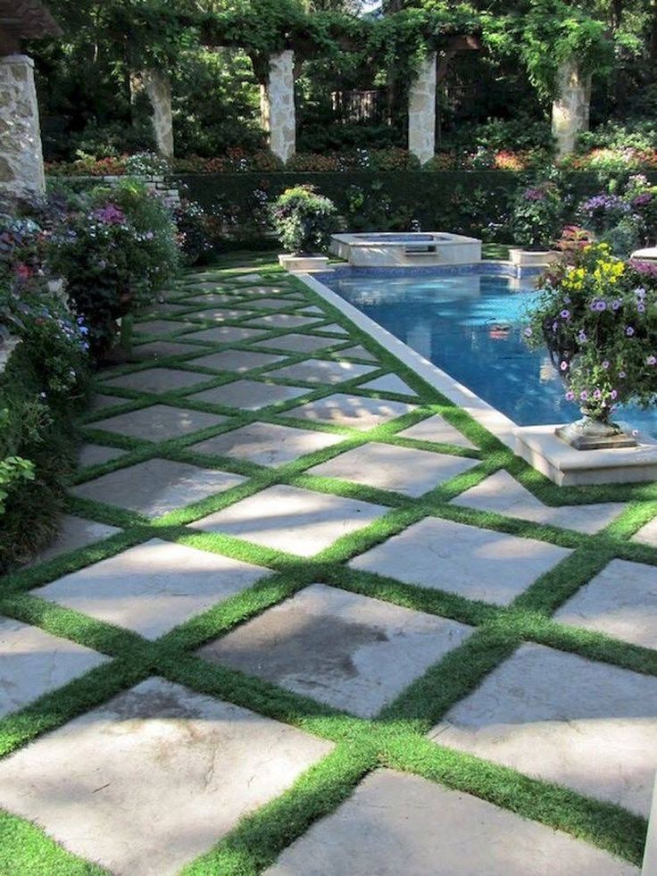 an outdoor swimming pool surrounded by greenery and stone pavers walkways that lead into the back yard