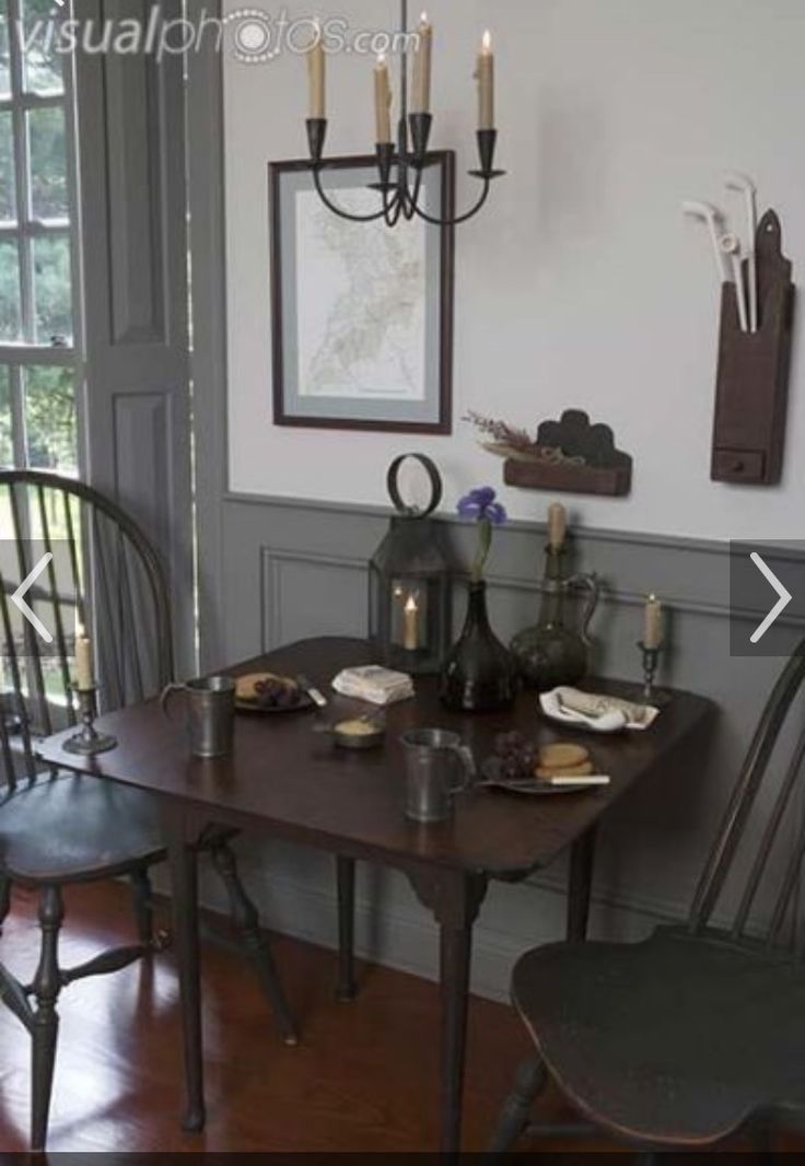 a dining room table and chairs with candles on the wall next to each other in front of a window