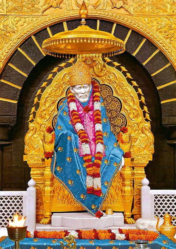 the statue is in front of an ornate gold structure with flowers and candles around it