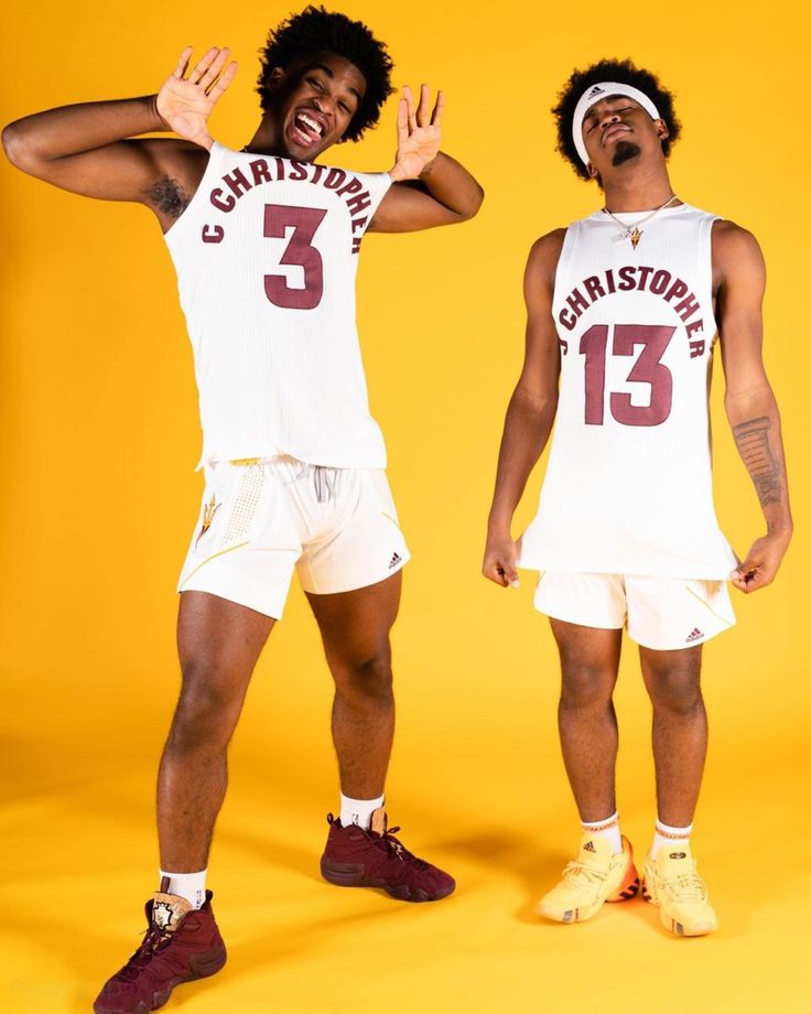 two men in basketball uniforms posing for the camera with their hands up and one holding his head