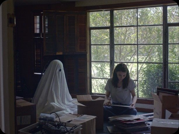 a woman sitting on top of boxes in front of a window with a ghost head