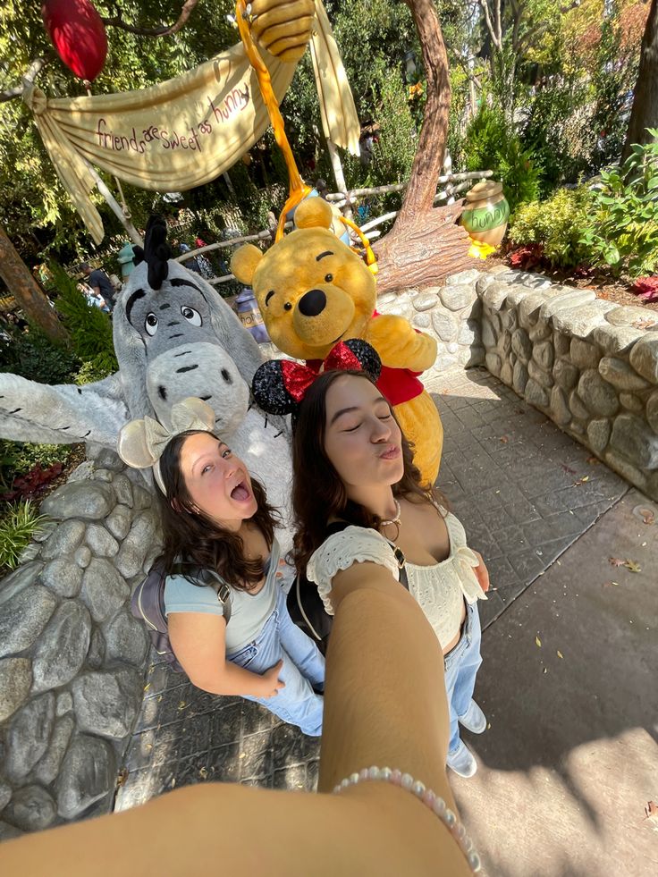 two girls are posing with winnie the pooh stuffed animals in front of their heads