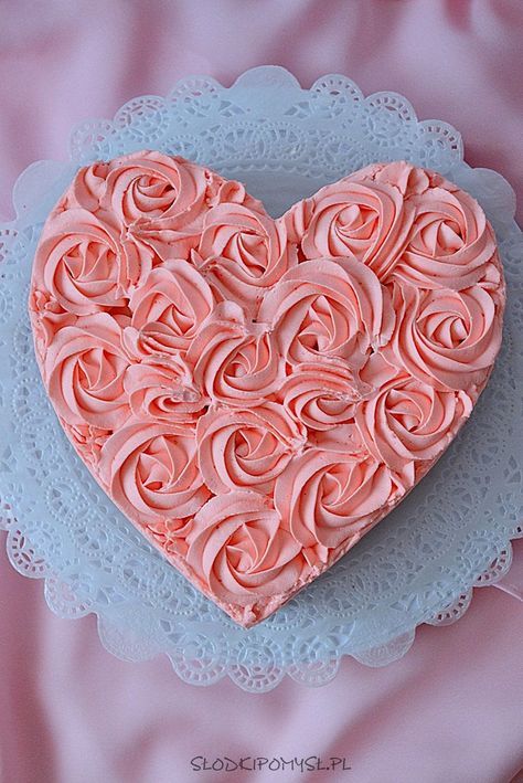 a heart shaped cake sitting on top of a blue doily covered plate with pink frosting