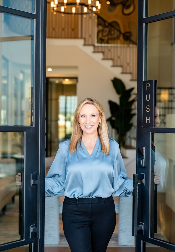 a woman standing in the doorway of a building with her hands on her hips and smiling