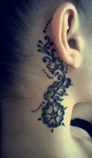 a woman with a tattoo on her neck and behind the ear is a flower design