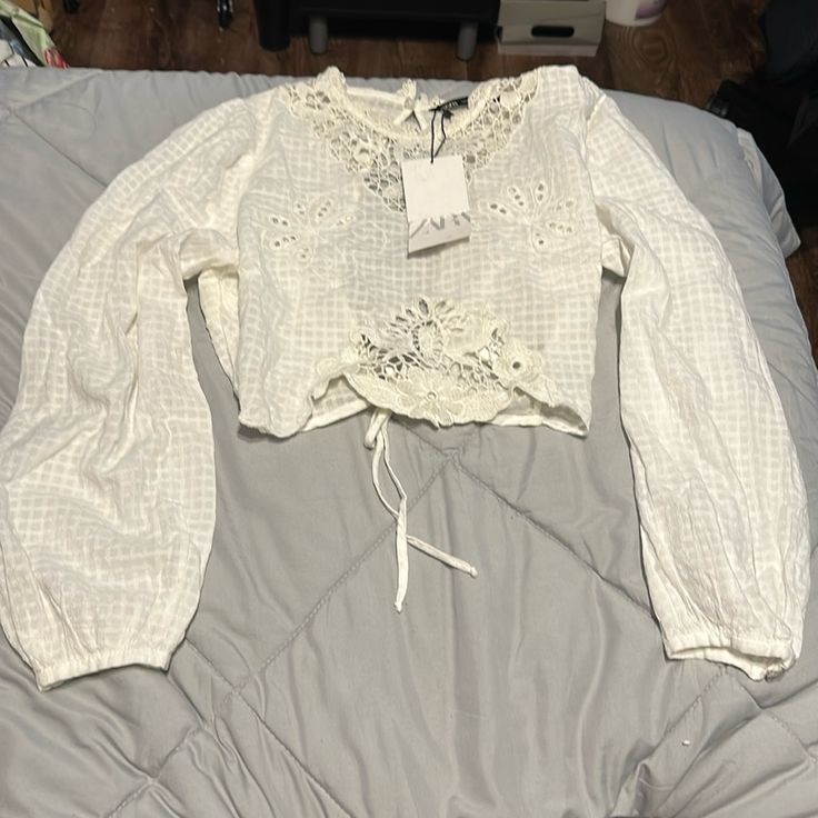 Brand New With Tags! Beautiful Blouse With Embroidery Detailing In The Front And Lovely Open Back That Ties At Waist. Has The Smallest Tear On Upper Back Right Shoulder. Fabric Is Very Delicate Summer Floral Embroidered Long Sleeve Lace Top, Summer Long Sleeve Lace Top With Floral Embroidery, Summer Long Sleeve Embroidered Lace Top, Long Sleeve Embroidered Lace Top For Summer, Summer Embroidered Long Sleeve Top With Lace Trim, Summer Long Sleeve Embroidered Top With Lace Trim, Casual Broderie Anglaise Shirt For Spring, Casual White Blouse With Lace Work, White Lace Top With Floral Embroidery And Long Sleeves