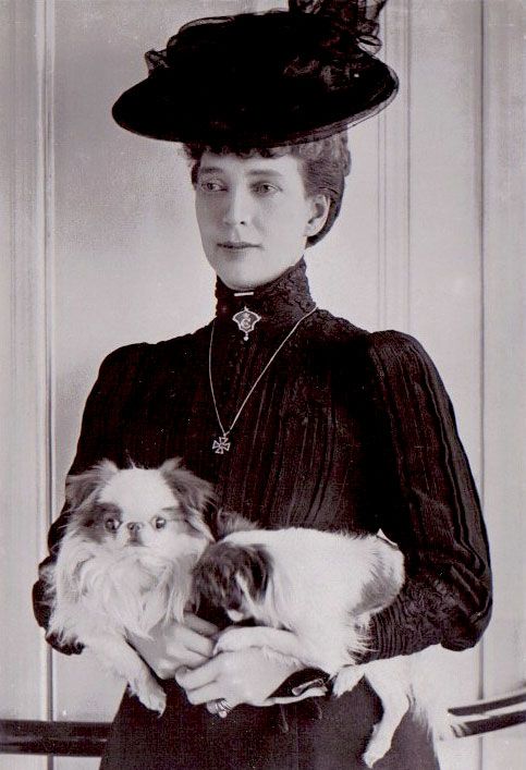 an old black and white photo shows a woman holding two dogs in her arms while wearing a hat