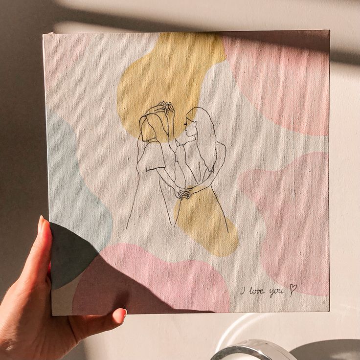 a hand holding up a card with a drawing of two people hugging each other on it