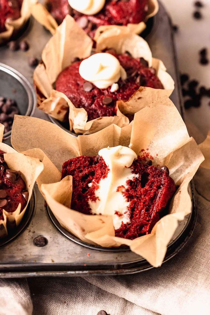 three cupcakes with red velvet and white frosting in muffin tins