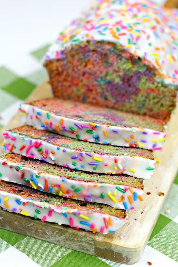 a loaf of cake with sprinkles sitting on top of a cutting board