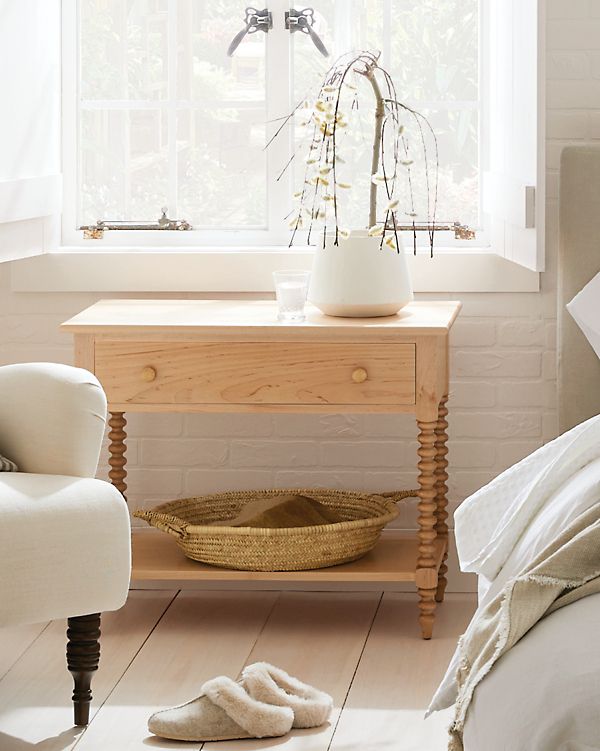 a bed room with a chair and a table next to a white brick wall in front of a window