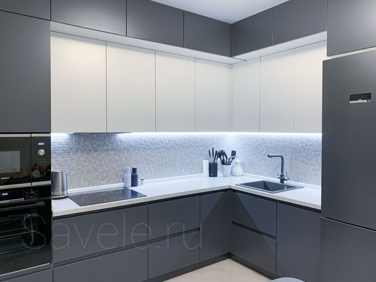 a modern kitchen with stainless steel appliances and white counter tops, along with gray cabinets