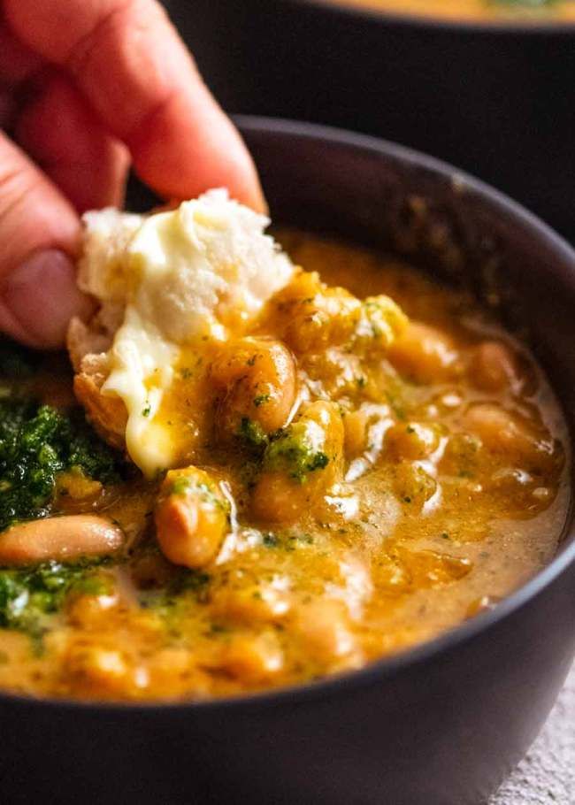 a person is dipping some kind of food into a bowl with broccoli and mashed potatoes