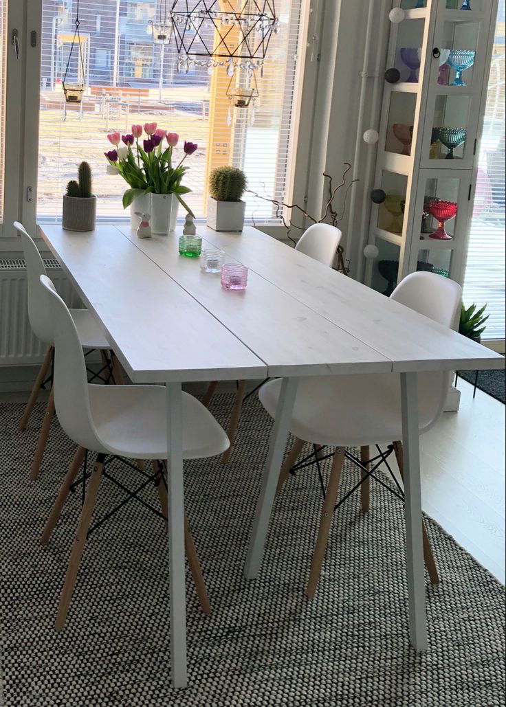 a dining room table with white chairs and flowers