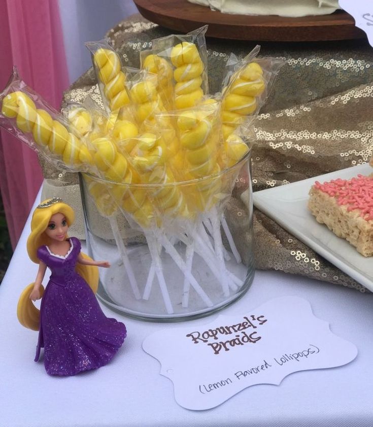 a table topped with cake pops and marshmallows next to a princess figurine