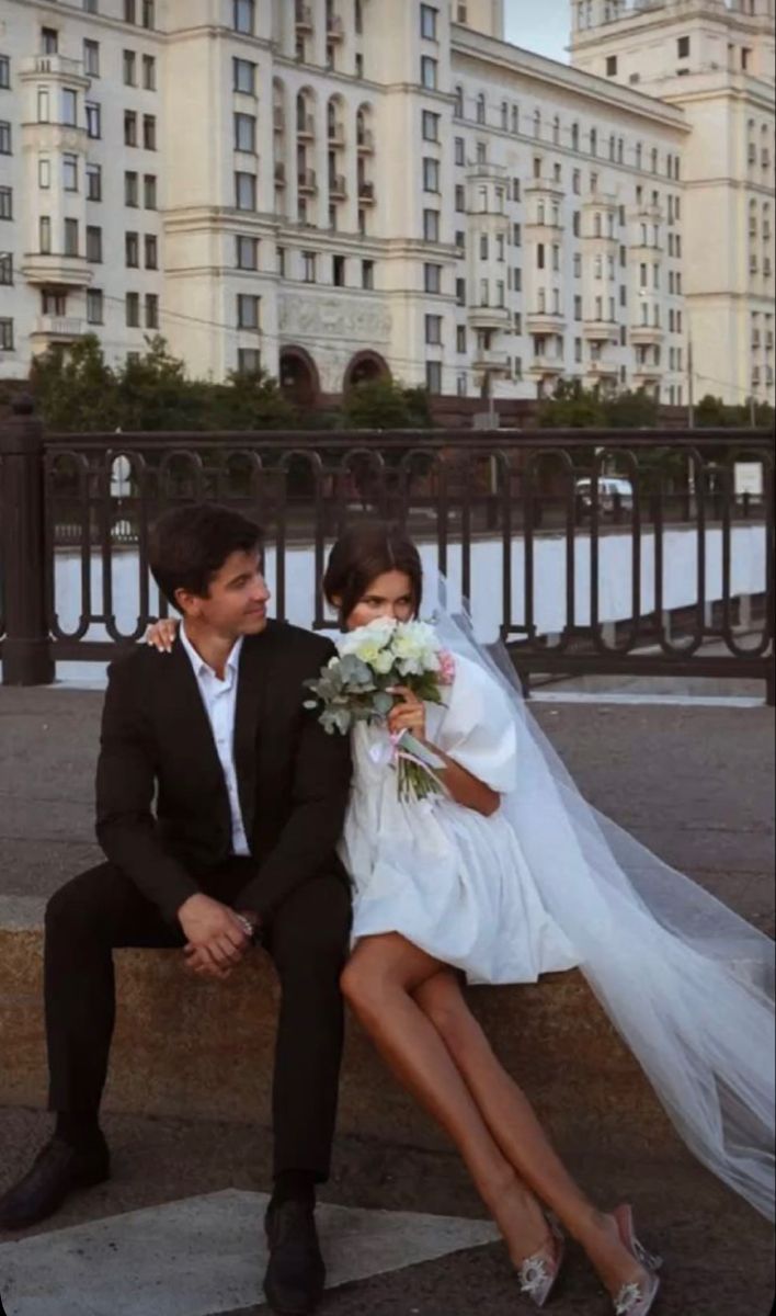 a bride and groom are sitting on a bench