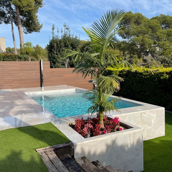 a palm tree in a planter next to a swimming pool with artificial grass on the ground