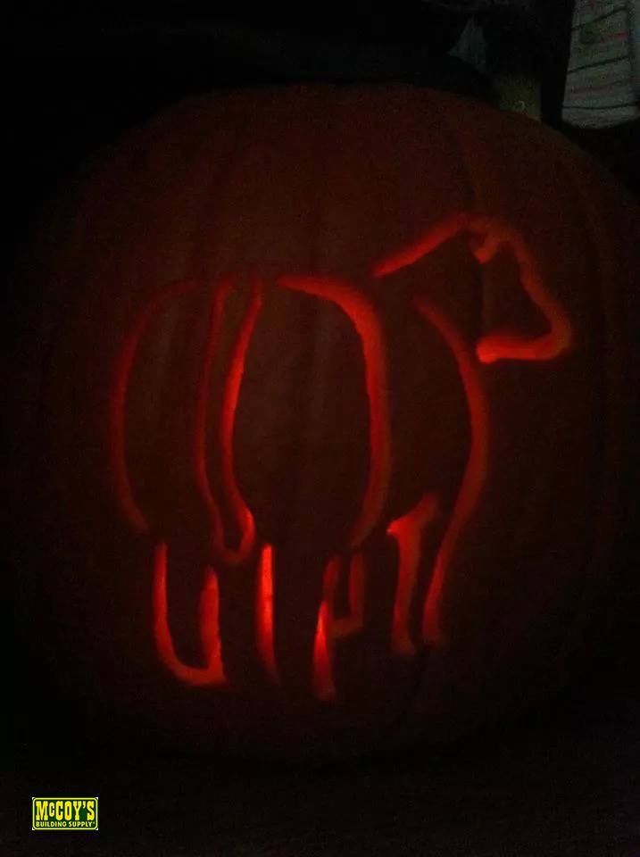 a pumpkin carved to look like a cow is lit up with red light in the dark