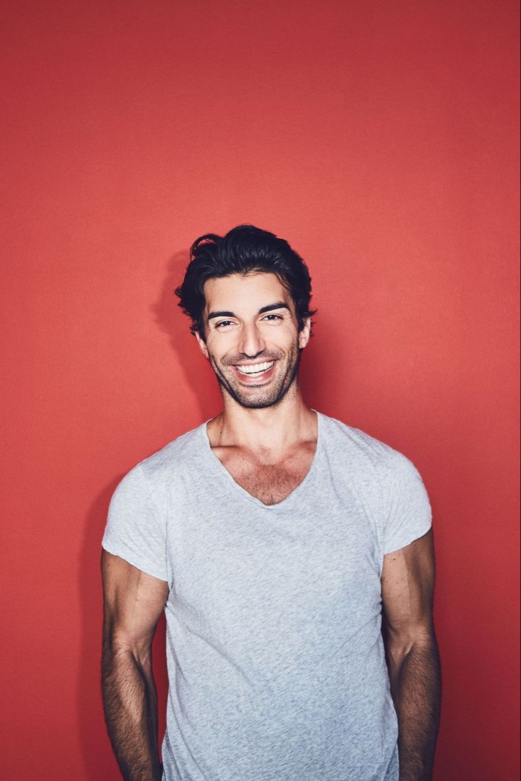 a man smiling while standing in front of a red wall