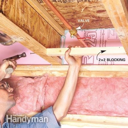 a man laying on top of a wooden floor under a roof with pink walls and insulation tape