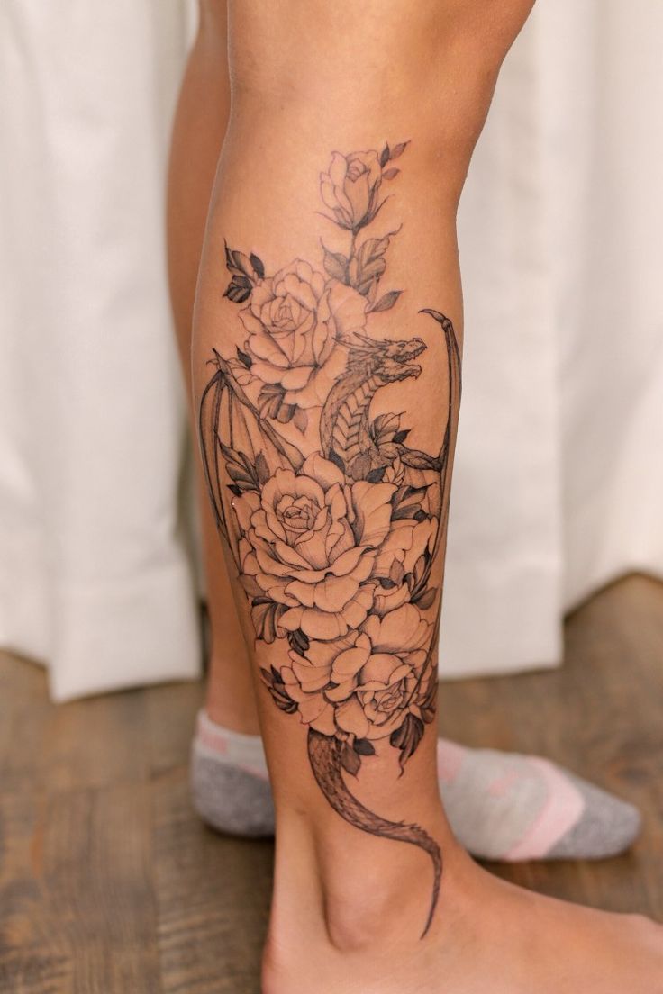 a close up of a person's leg with flowers on it and a snake