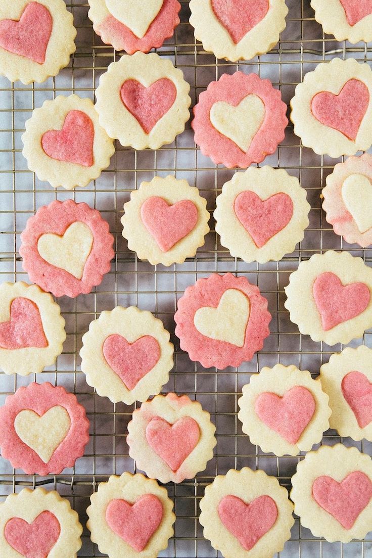 heart shaped cookies on a cooling rack with hearts in the middle and pink frosting