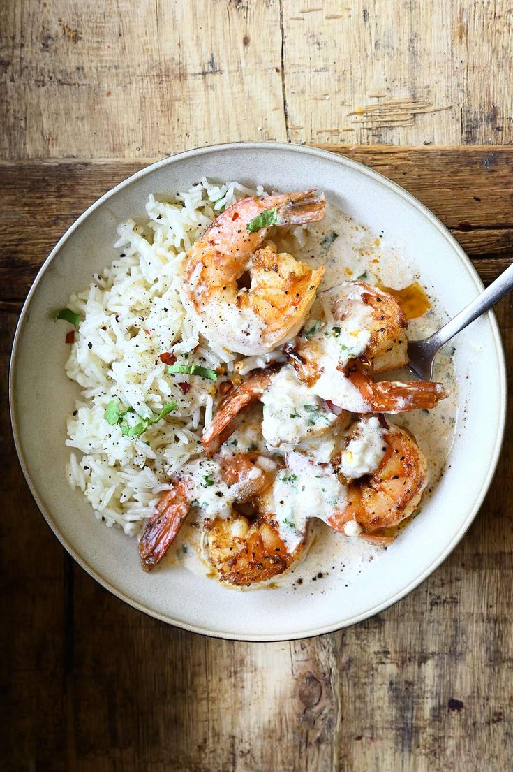 a bowl filled with rice and shrimp on top of a wooden table