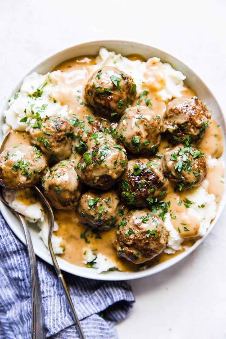 a bowl filled with meatballs and gravy on top of mashed potatoes