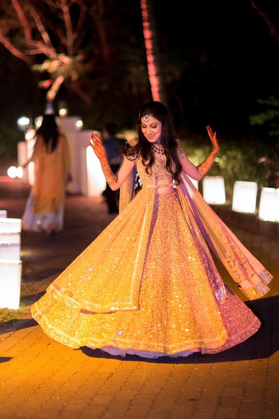 a woman in a yellow dress dancing on the street at night with her arms outstretched