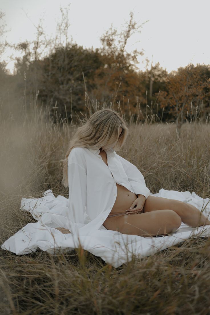 a woman sitting on top of a blanket in a field