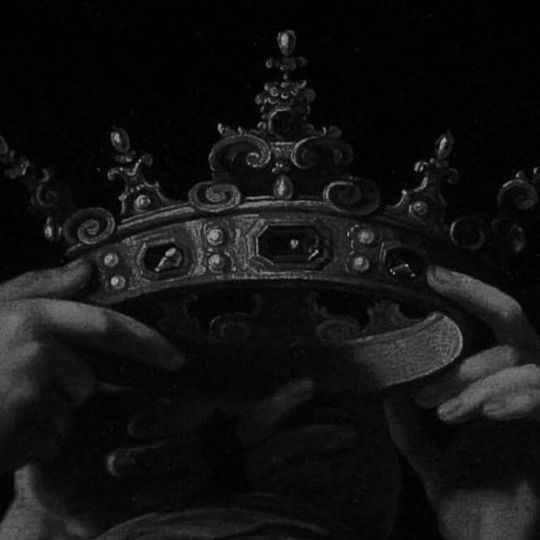 black and white photograph of a person holding a crown in front of their face with both hands