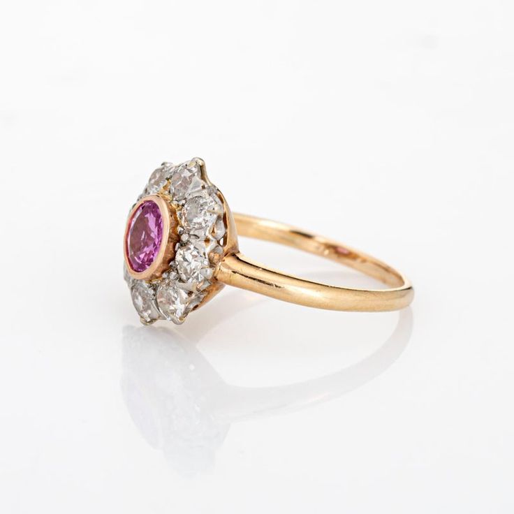 Stylish antique Edwardian pink sapphire & diamond cluster ring crafted in 14k yellow gold (circa 1900s to 1910s). One centre set pink sapphire is estimated at 0.50 carats, accented with eight estimated 0.15 carat old mine cut diamonds. The total diamond weight is estimated at 1.20 carats (estimated at I-J and SI1-I1 clarity). The sapphire is in very good condition and free of cracks or crisps.   The classic cluster design highlights a halo of diamonds surrounding the vibrant and lively pink sapp Old Cut Diamond Ring, Classic Pink Cluster Ring For Formal Occasions, Classic Pink Cluster Ring With Center Stone, Classic Ruby Ring With Rose Cut Diamond Cluster, Classic Pink Diamond Cluster Ring, Classic Pink Cluster Ring With Halo Setting, Classic Pink Ruby Ring With Halo Setting, Classic Pink Cluster Ring With Prong Setting, Vintage Ruby Cluster Ring With Center Stone