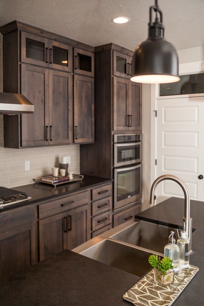 a kitchen with dark wood cabinets and black counter tops, an island in the middle