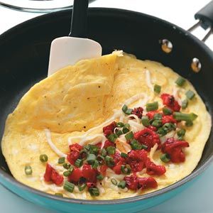 an omelet with tomatoes and green onions in a skillet