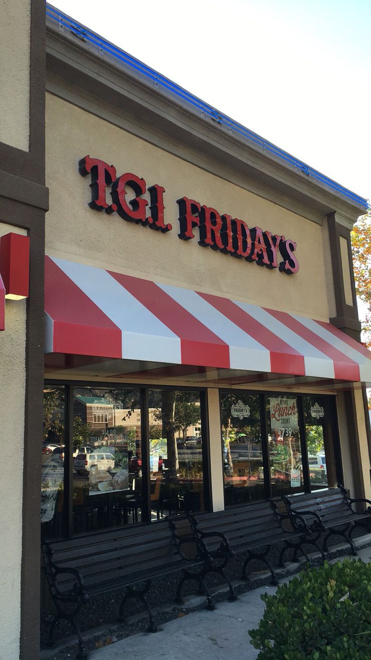 the front of a restaurant with benches outside and red and white striped awnings