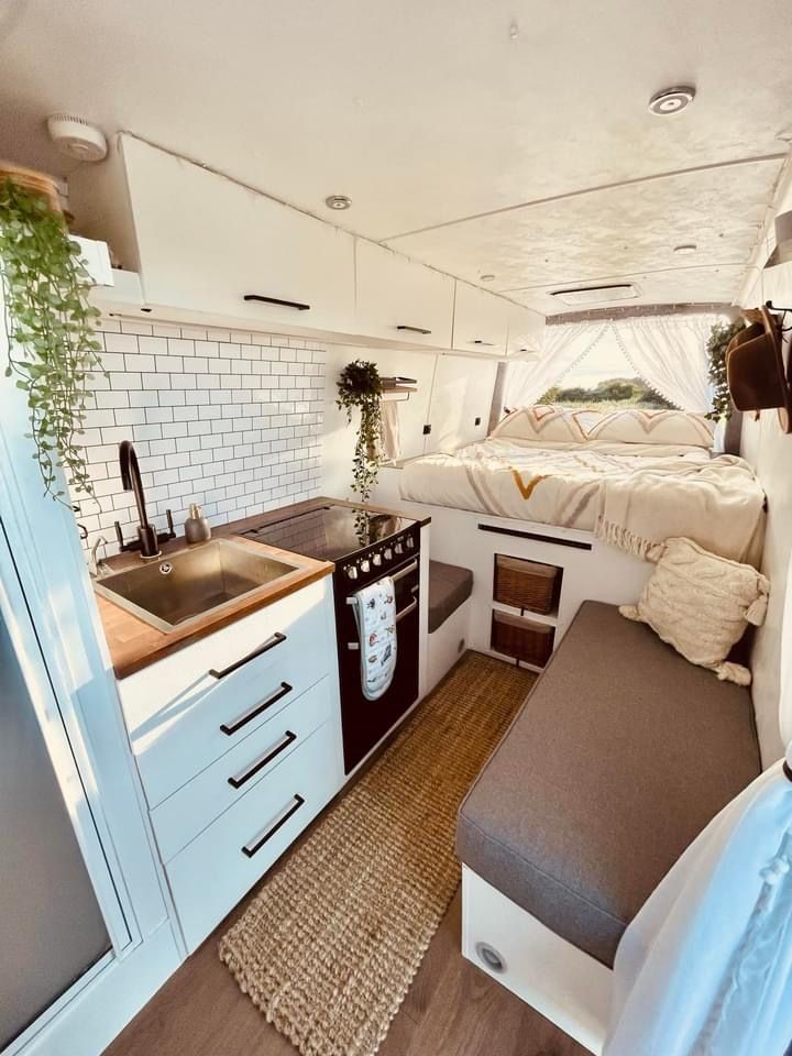 the interior of a camper with a sink, stove and bed in it's center