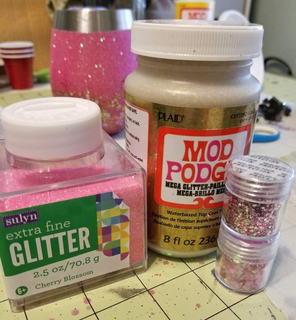 some crafting supplies are sitting on a counter top, including glue and glitter bottles