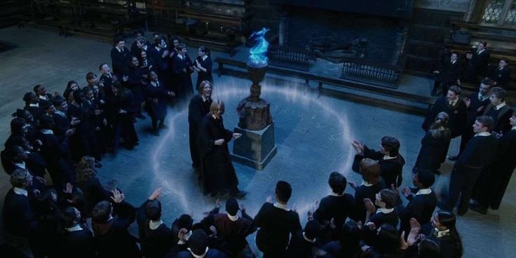 a group of people standing around each other in front of a large screen with harry potter on it